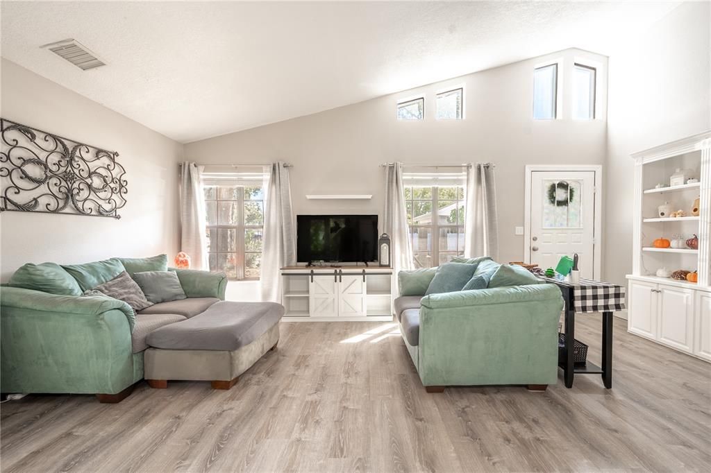 The living room with vaulted ceiling and transom windows for natural light.