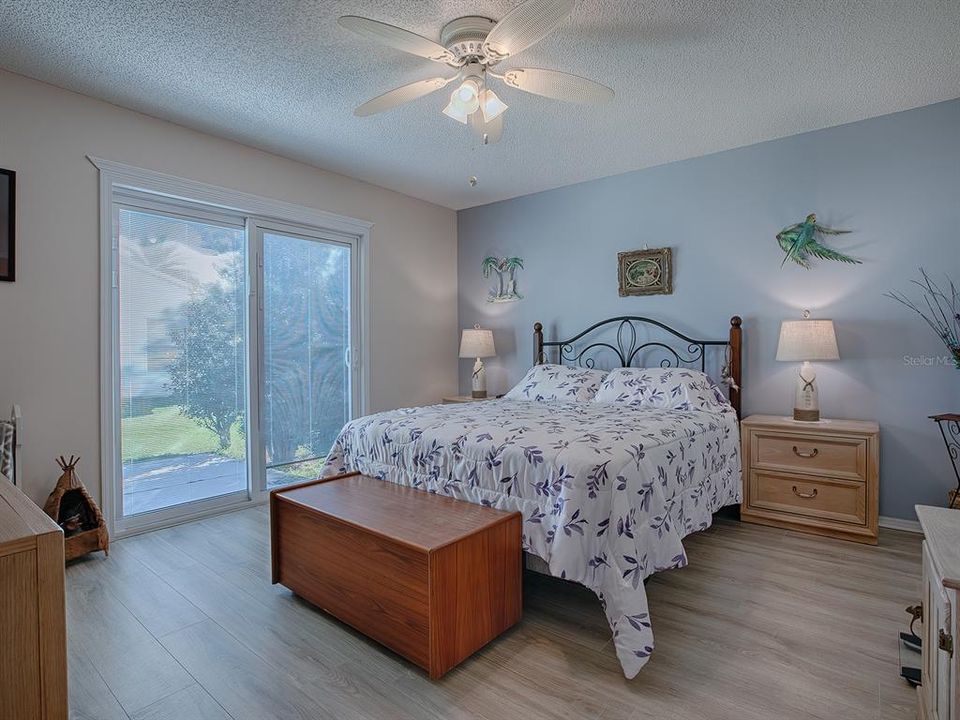 LOVELY MASTER BEDROOM HAS GLASS SLIDERS THAT LEAD TO THE PATIO