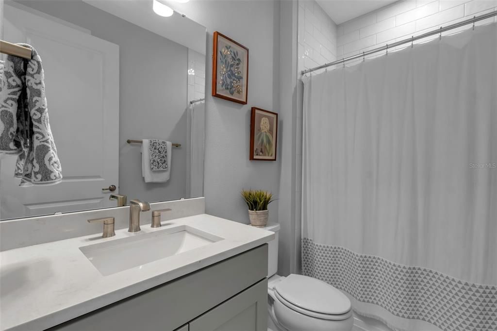 Guest bath with tile to ceiling, quartz top vanity and comfort height toilet