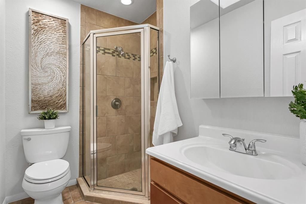 The en suite bath features neutral color tile