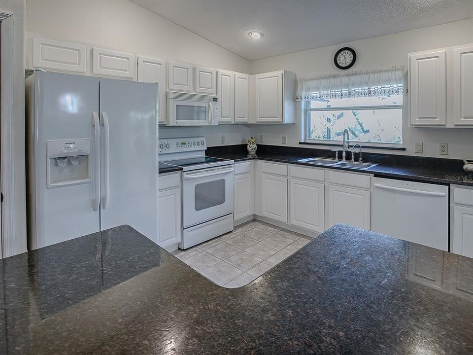 BEAUTIFUL GRANITE COUNTERS AND STAINLESS, DOUBLE-BASIN SINK WITH A WINDOW VIEW