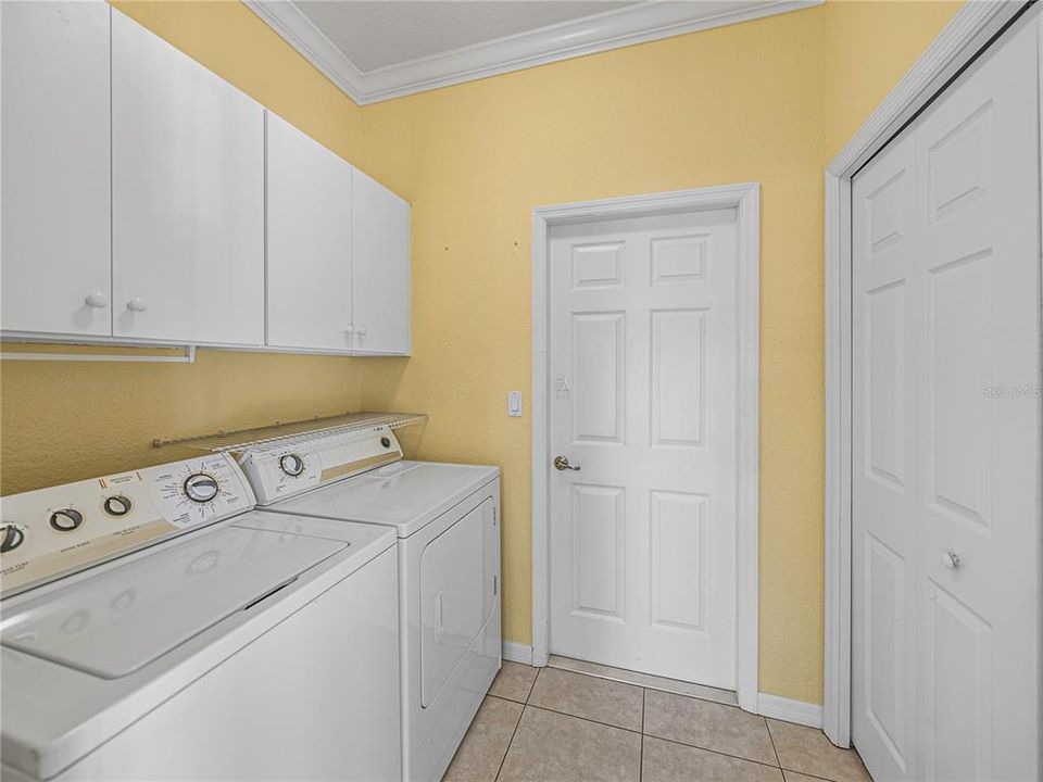 Laundry room with large closet and storage cabinets above washer and dryer which convey