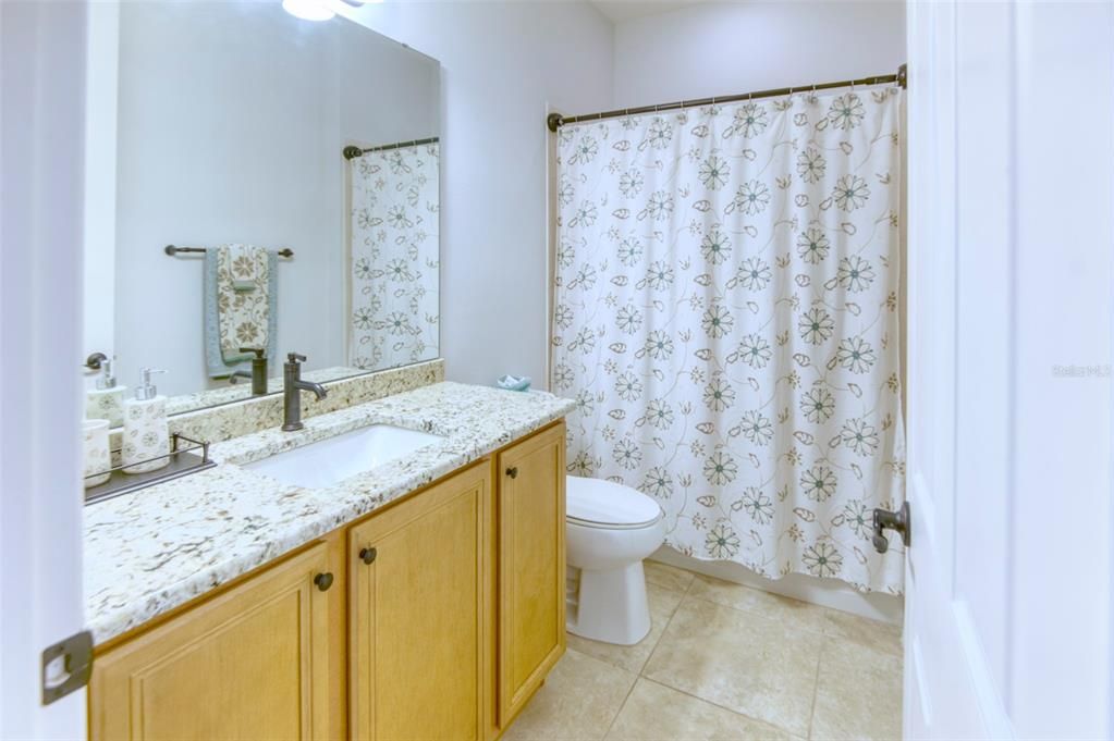 The 2nd full bath is outfitted the same as the primary - granite counter, under mount sink, bronze accents