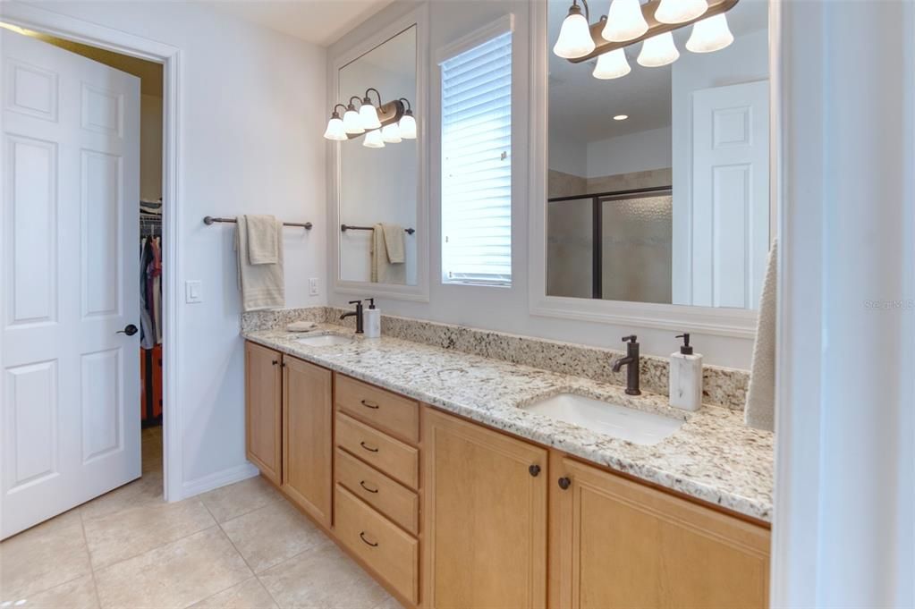 Primary bath features granite counters, under mount large bowl sinks, single handled oil-rubbed bronze fixtures, large framed mirrors, and a fixed pane window to flood the room with light!