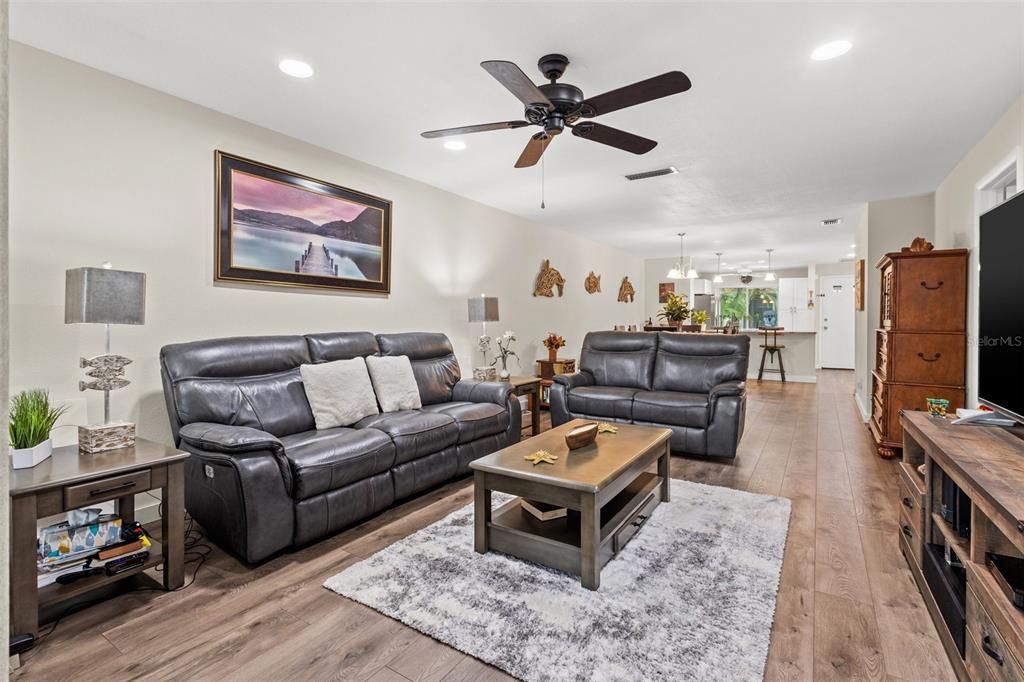 Living room ares features a ceiling fan and recessed lighting.