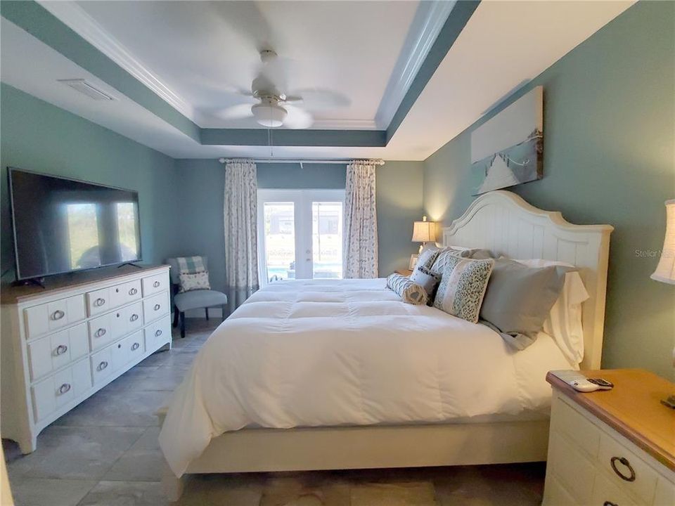 Master Bedroom has Tray Ceiling and Crown Moulding with French Doors out to Lanai and Pool