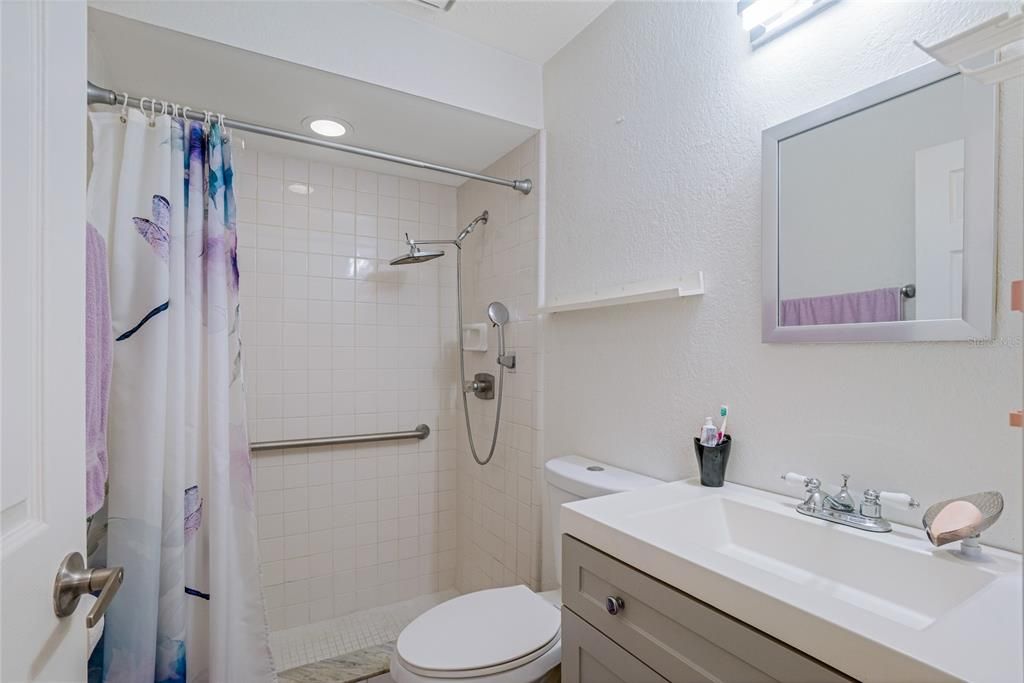 Primary bathroom with step down shower. Has handlebars and updated shower head. Updated vanity