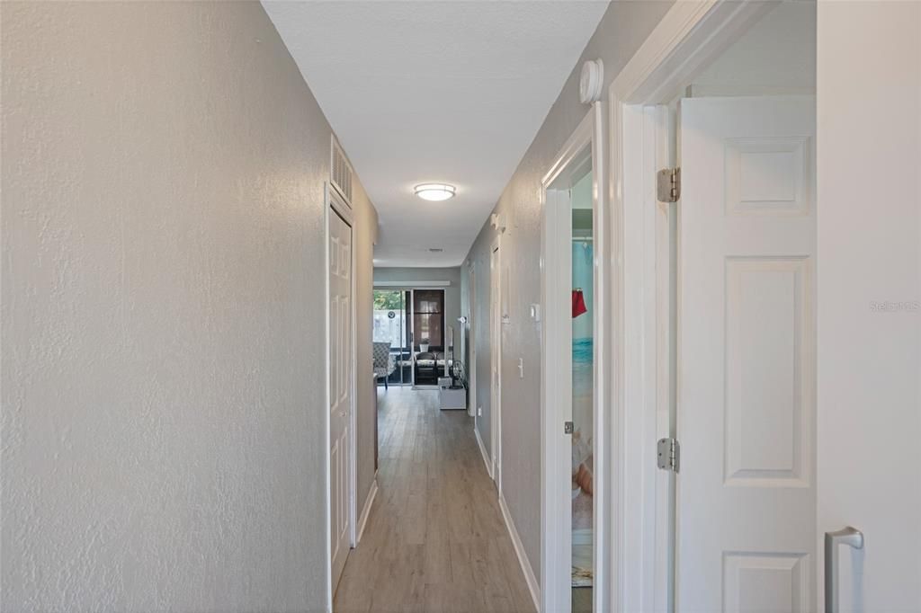 POV from front door- hallway leading to bedrooms, bathroom, living room & kitchen. Updated luxury vinyl flooring throughout entire home.