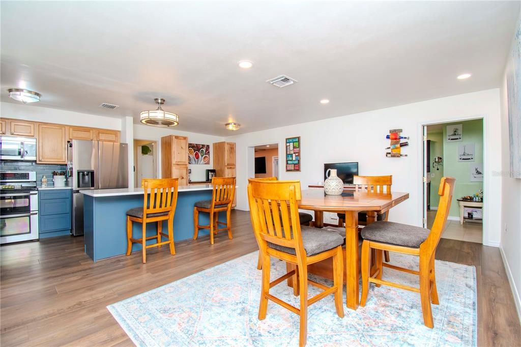 View of dining area, door into the primary ensuite and bedroom and remodeled kitchen and coffee station area.