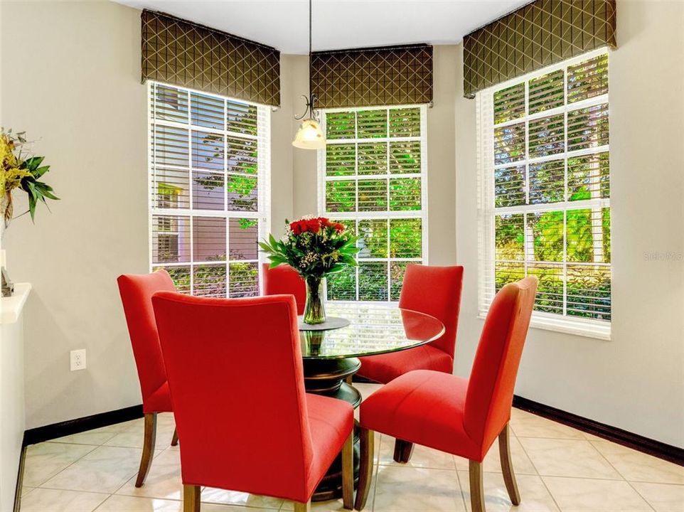 The cozy dining nook has three large windows overlooking the lush landscaping.