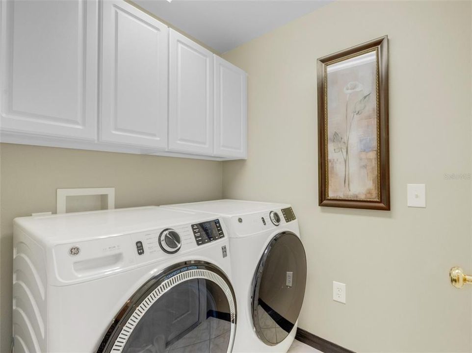 The inside laundry room with front loading washer & dryer plus overhead cabinet storage.