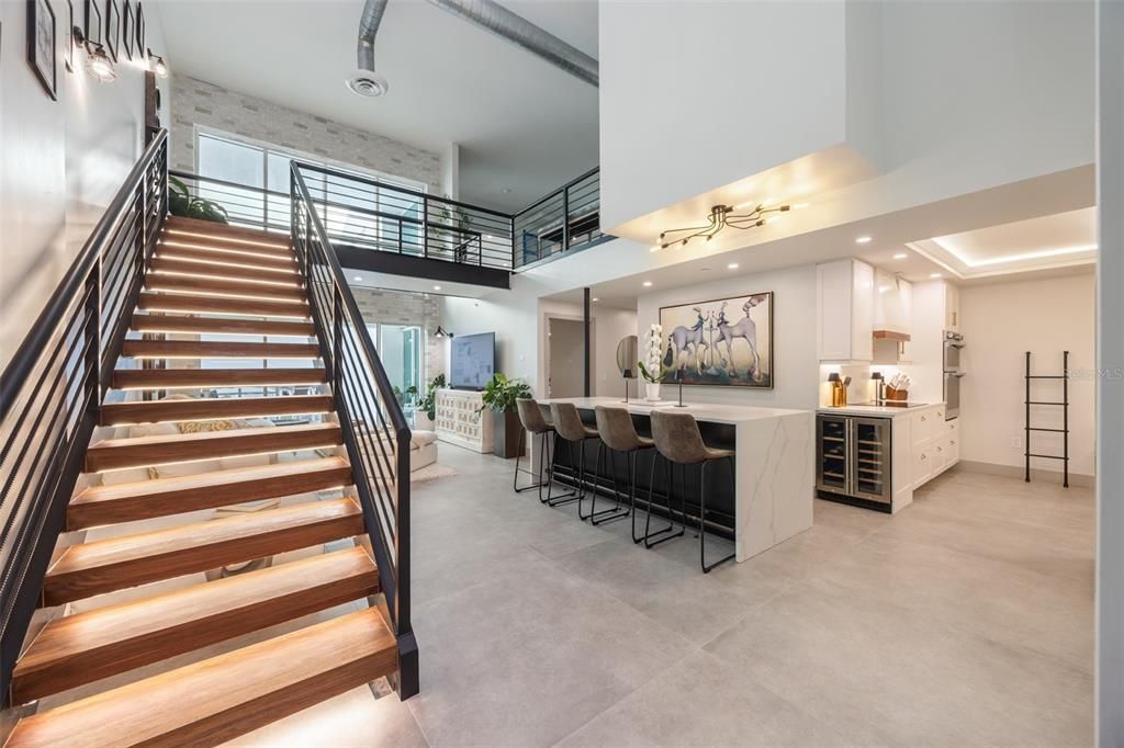 Backlit, solid walnut floating staircase wraps around the living room and kitchen, acting in both function and decor