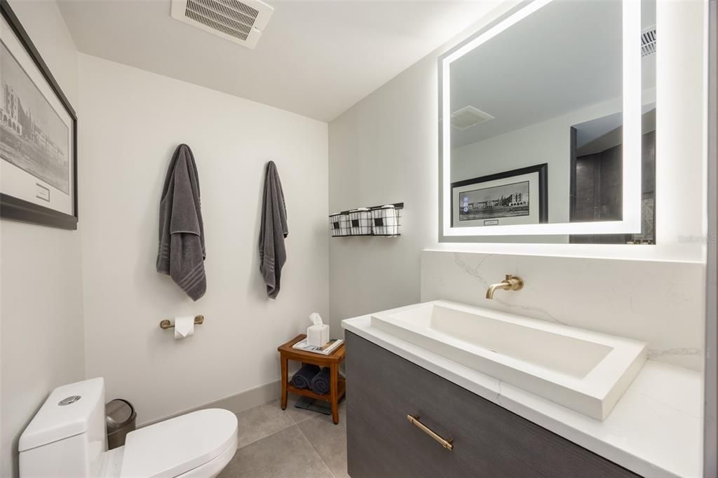 First floor bath with updated backlit mirror and custom undercut cabinet and fully remodeled shower