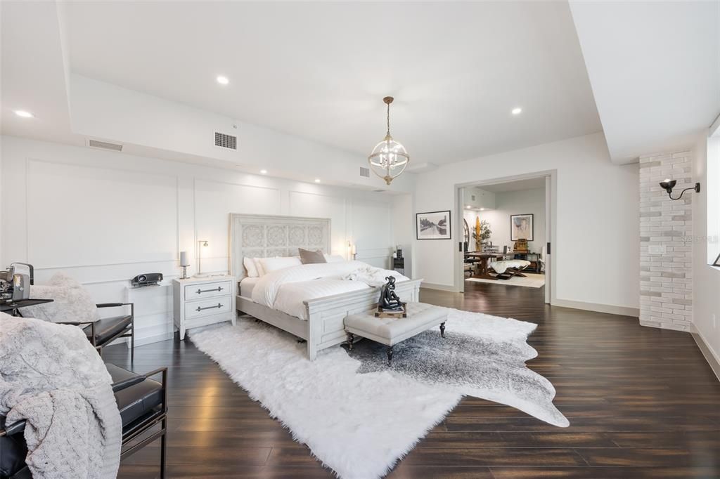 Large primary bedroom with beautiful lighting and exposed brick support walls