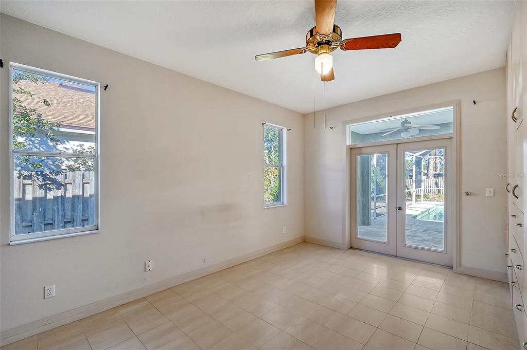 Primary bedroom with french doors to the lanai and pool area