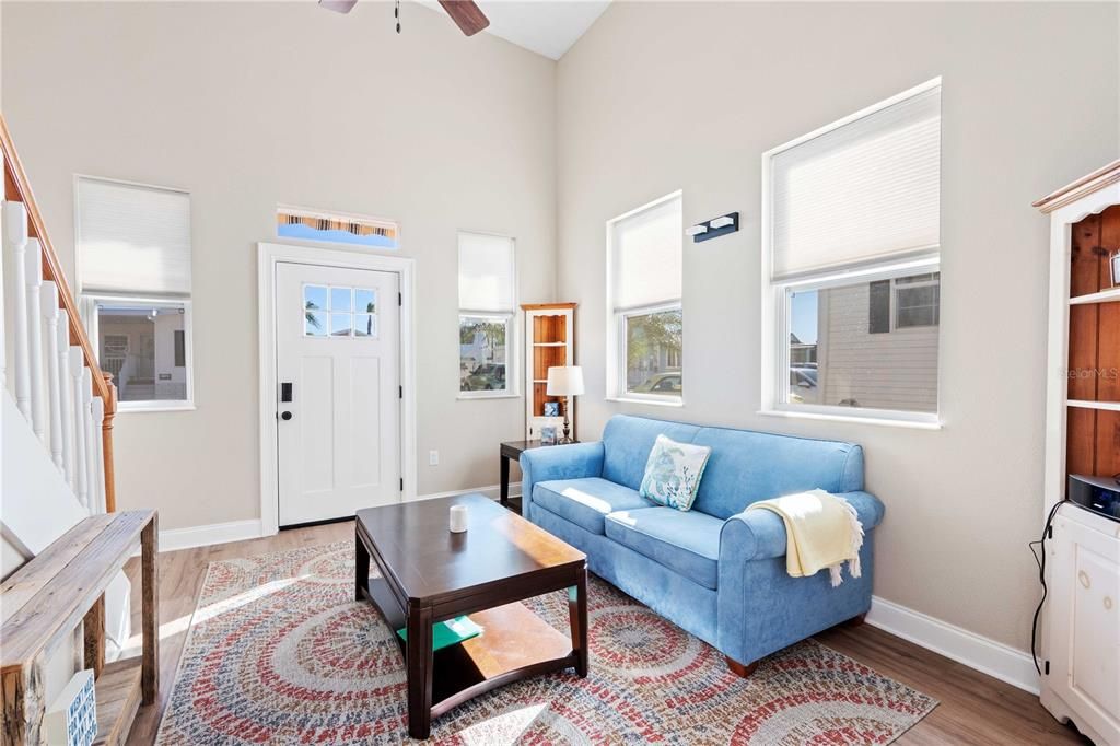 This living room is open with kitchen and offers 14' ceiling, ceiling fan, custom lighting, drywall construction, and so much more.