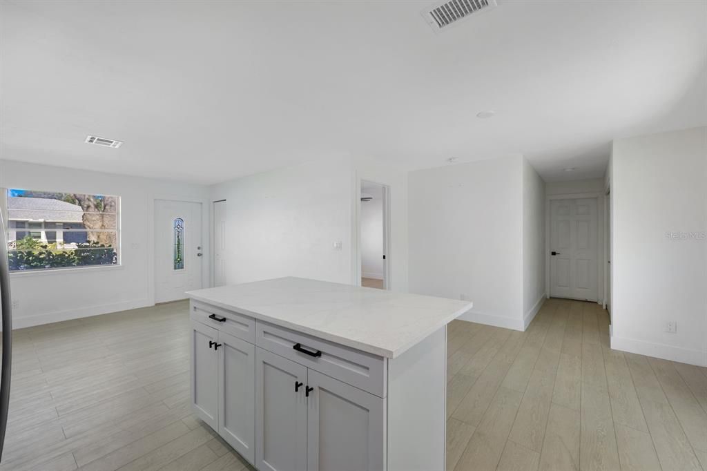 Kitchen with a kitchen island, light stone counters, and light wood-type flooring