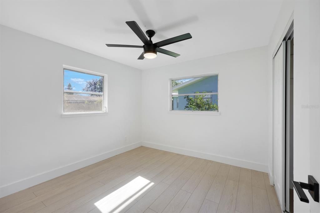 Empty room with light hardwood / wood-style floors, plenty of natural light, and ceiling fan