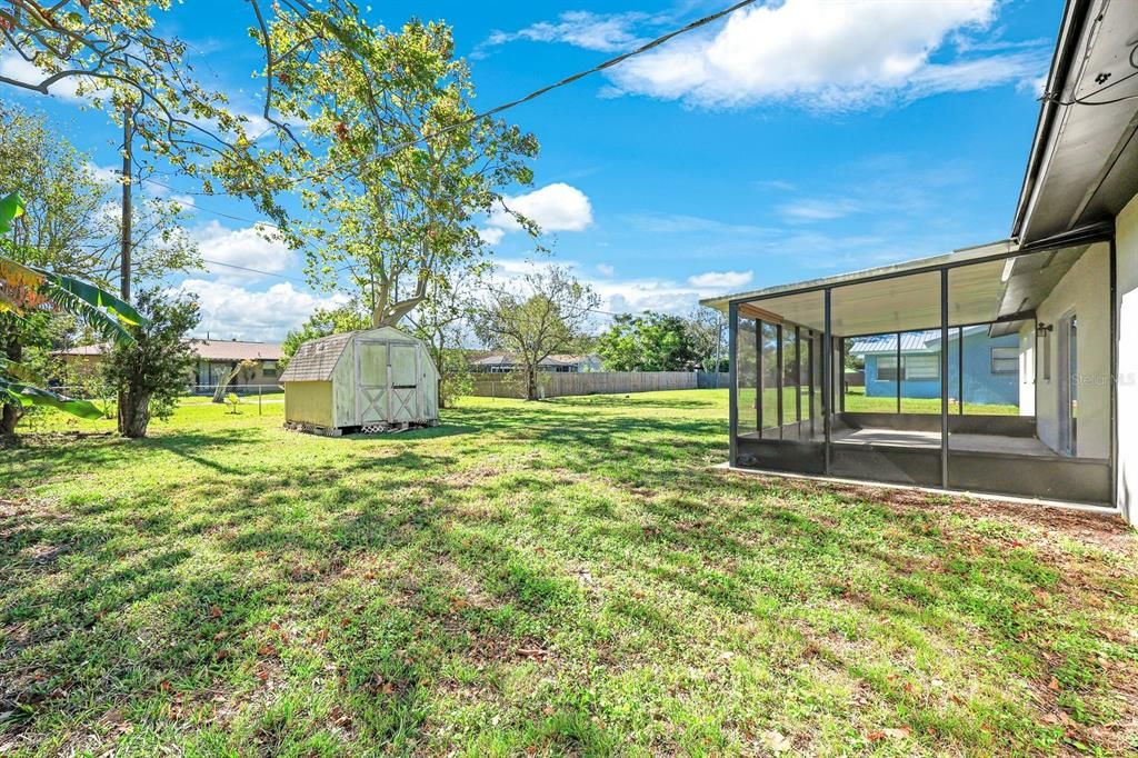 View of yard featuring a sunroom and a storage shed