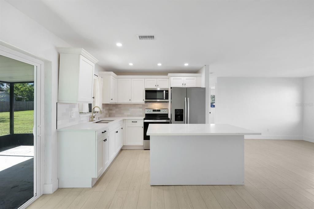 Kitchen featuring light wood-type flooring, stainless steel appliances, a kitchen island, sink, and white cabinetry