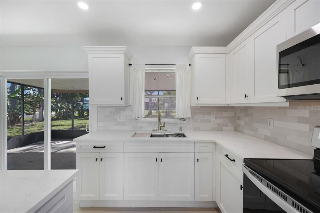 Kitchen featuring backsplash, white cabinetry, sink, and appliances with stainless steel finishes