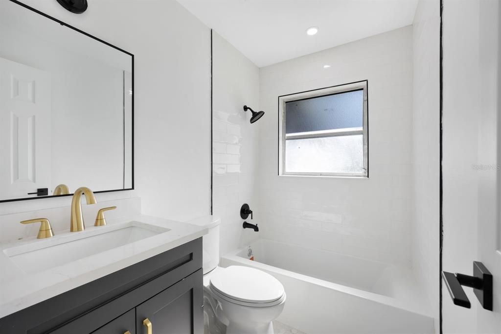 Full bathroom with vanity, tiled shower / bath combo, and toilet