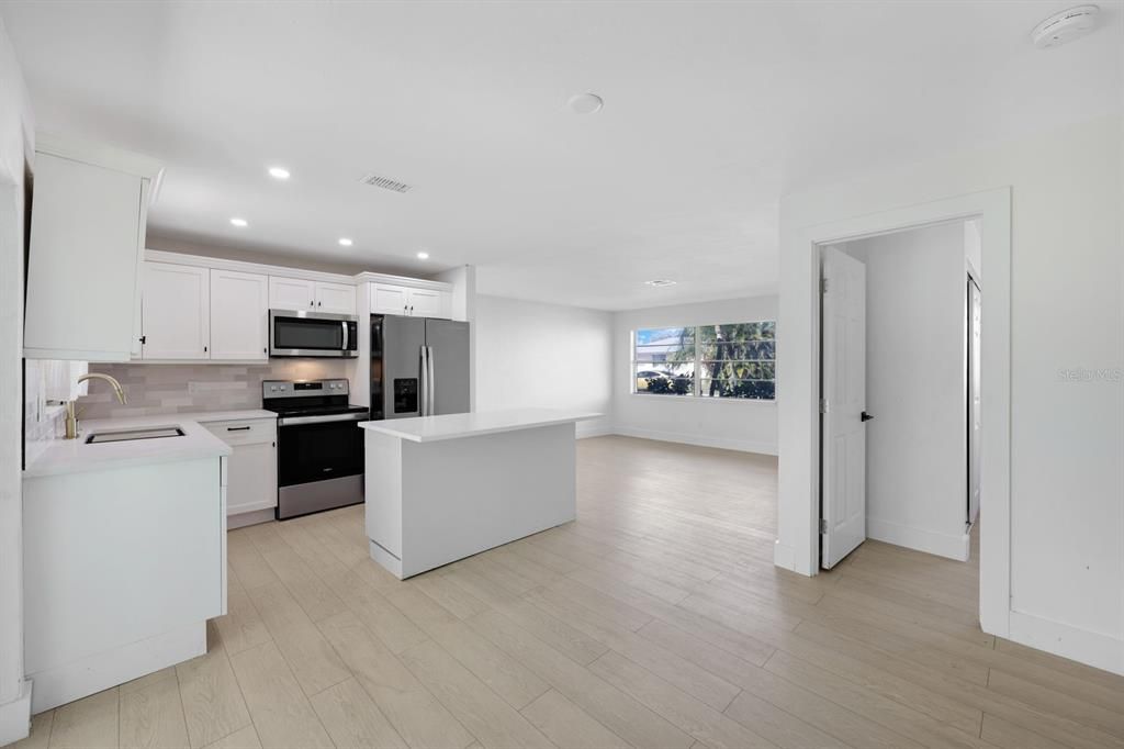 Kitchen featuring white cabinetry, sink, stainless steel appliances, light hardwood / wood-style flooring, and a kitchen island