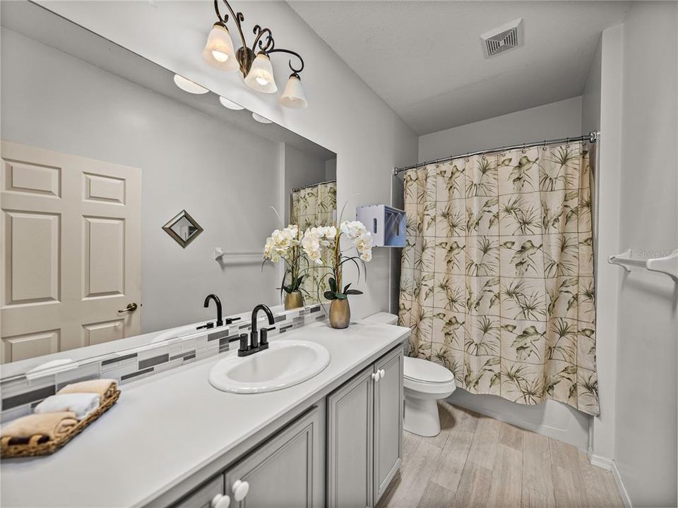 Guest bathroom with tub and tile surround shower.