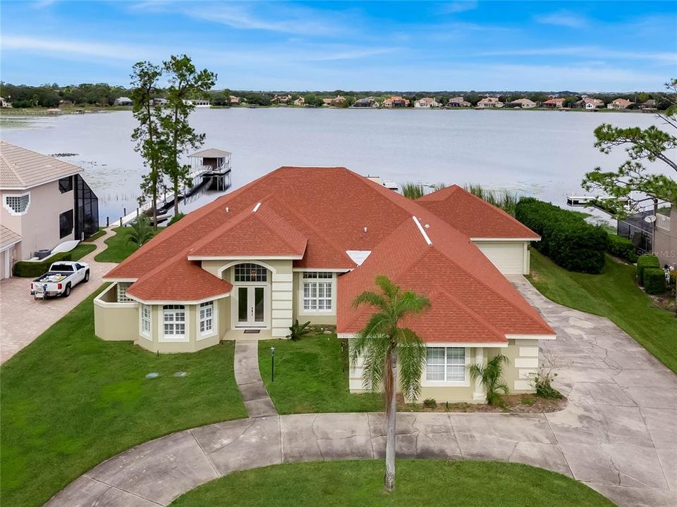 Front exterior of home with lakefront, wrap-around driveway.