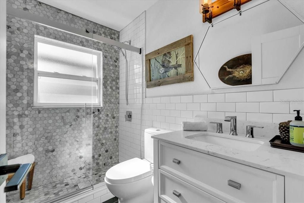 Upgraded vanity with solid surface top, under mount sink.  Beautifully tiled to the ceiling. High end frameless shower door.