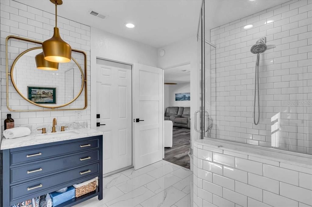 Upgraded vanity with marble top, under counter sink, gold accents and entrance to the garage, marble style porcelain tile