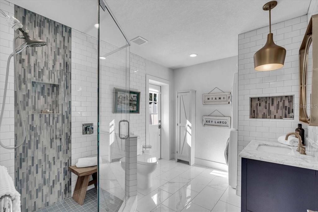 Exceptional tiled bath with heated towel warmer and entrance to the back yard with laundry