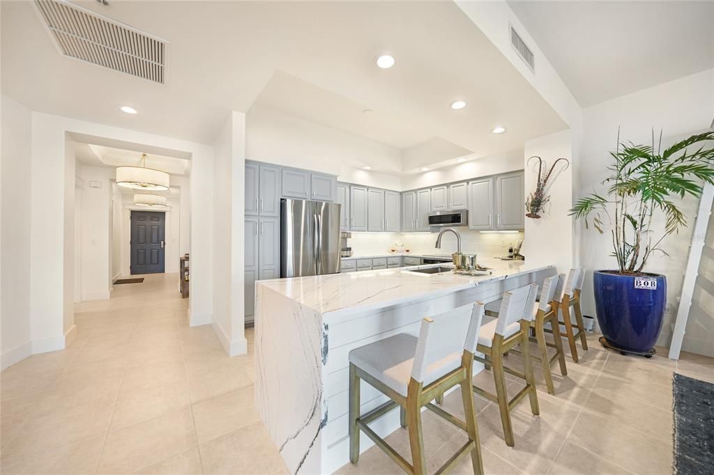 Large kitchen with wood, soft close cabinets. The cabinet doors and drawers have marble pulls and handles. Waterfall island with all stainless steel appliances.