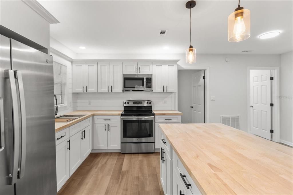 Renovated Kitchen with NEW: White Shaker Cabinets w/ Crown Molding & Lighting, Butcher Block Countertops, Shiplap Backsplash, Center Island w/ Breakfast Bar, Pendant Lighting & Newer S/S Appliances