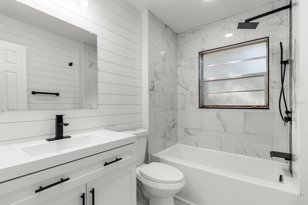 Renovated Full Bath... Tub/Shower Combo w/ NEW Tile Surround & Accent Stripe, NEW Vanity, NEW Center Flush Toilet & NEW Plumbing Fixtures including Rainfall Shower Head, Handheld Shower Wand & Waterfall Tub Spout