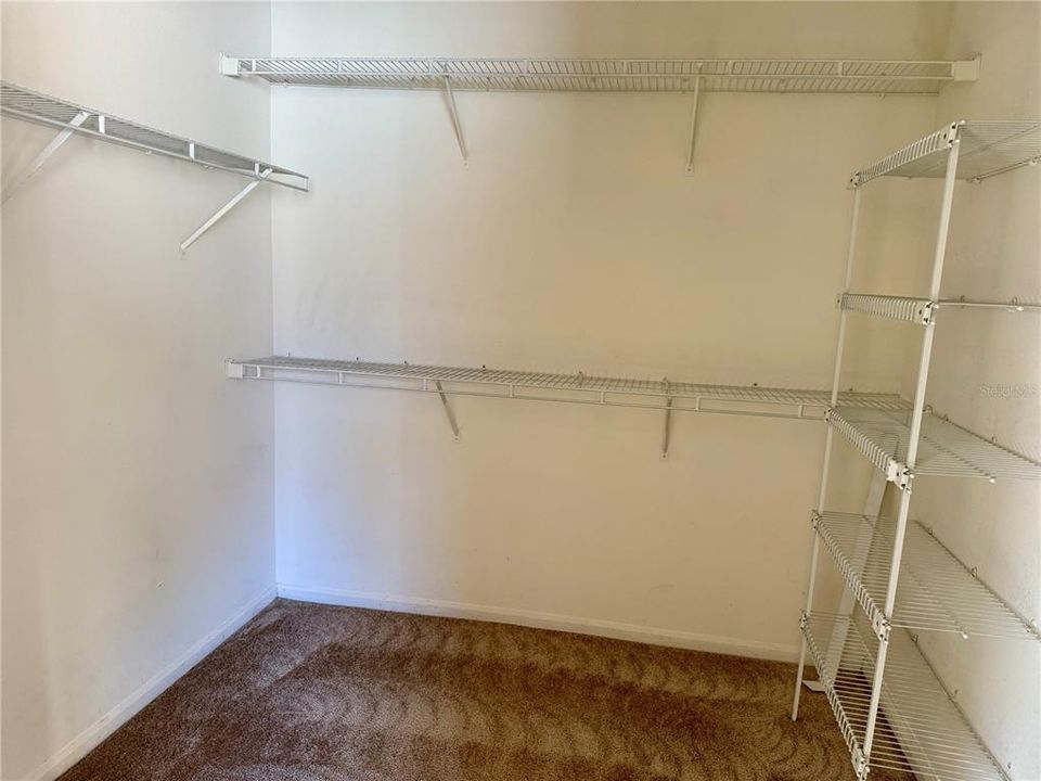 Primary walk in closet with a lot of shelves