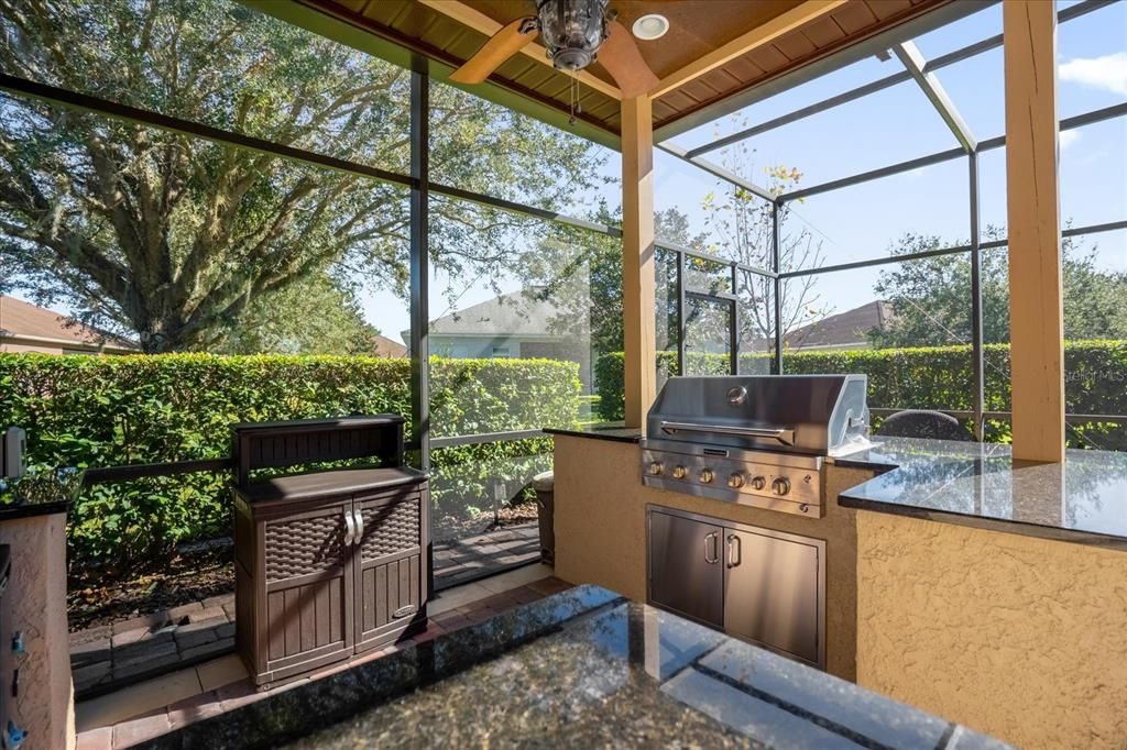 Outdoor kitchen with built-in grill, refrigerator, granite countertops, fan and lighting