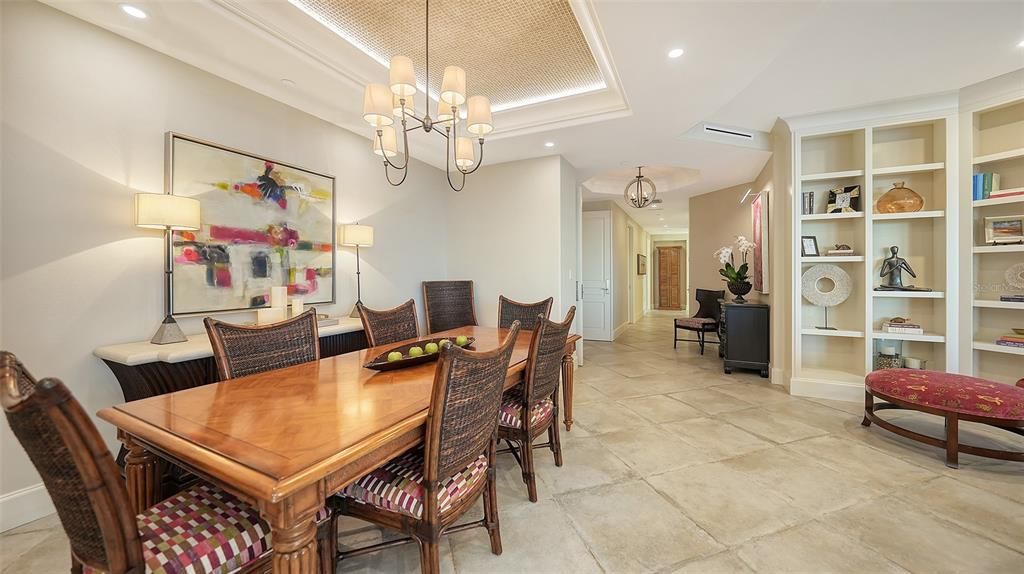 Dining room, opening to living area, room to expand the table, bronze chandelier. Wallpaper detailing in tray ceiling with  lighting. Original artwork.