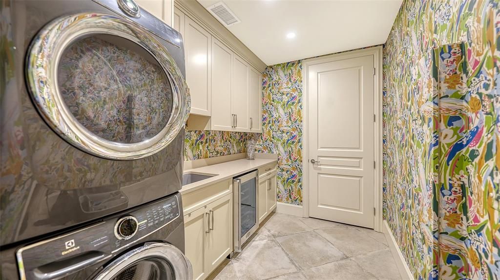 Fun laundry with large stack washer and dryer, storage cabinetry and sink.  Utility closet.