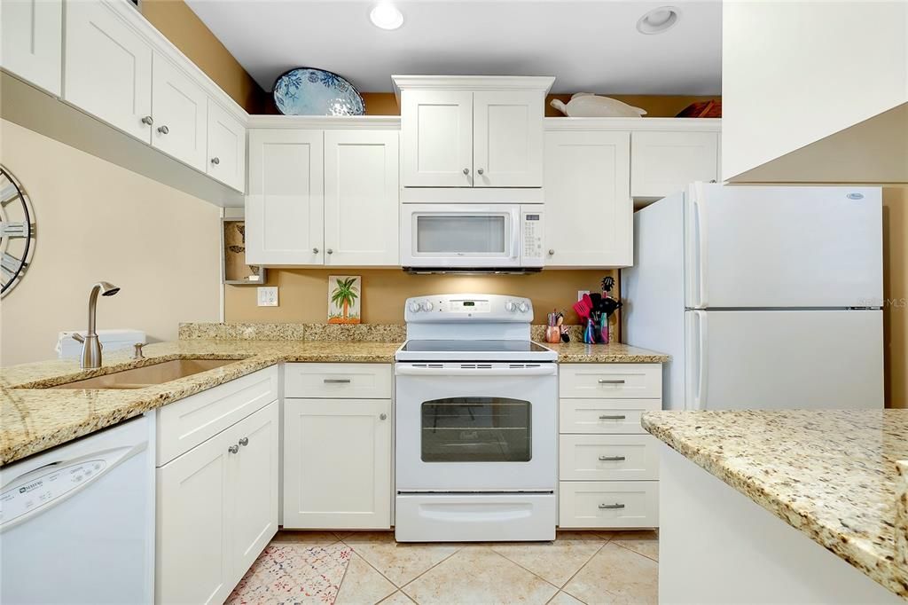 Kitchen has granite counters and tile floors.