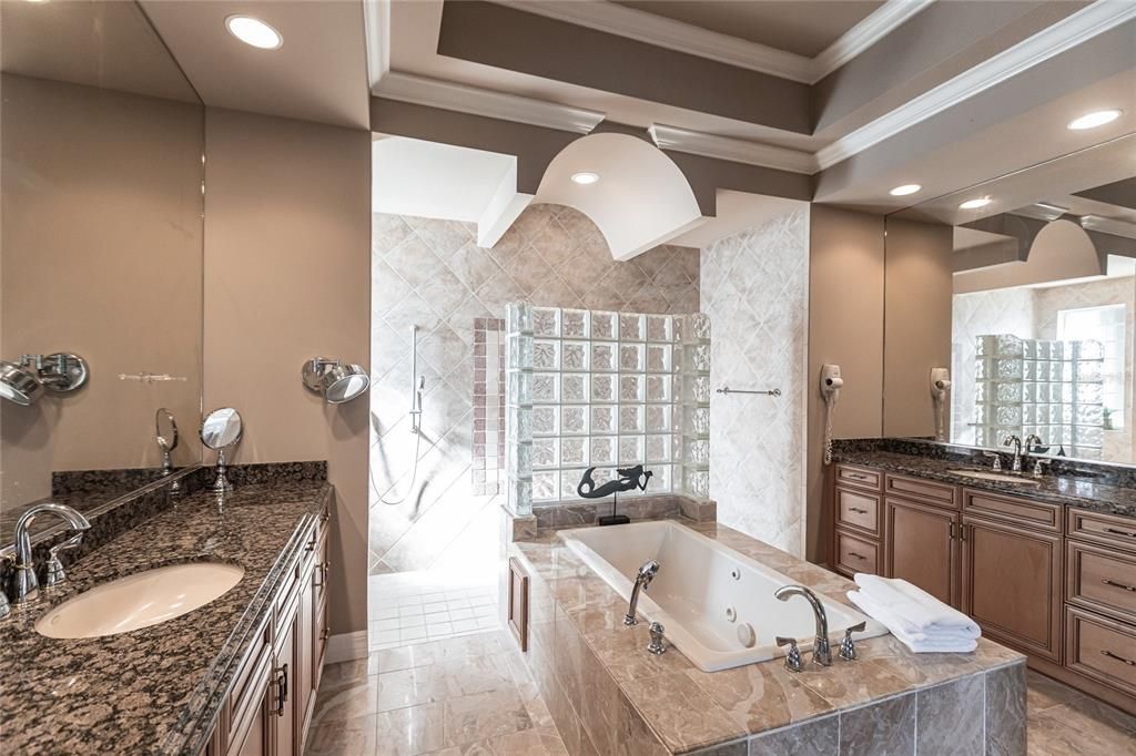 The spa-inspired primary bath offers a jetted garden tub, a dual-entry shower with twin showerheads, split vanities, and a private water closet.