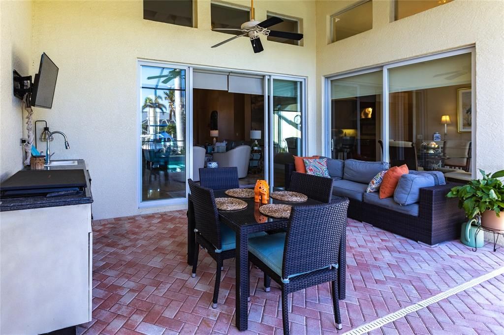 Step outside to your personal paradise. The expansive lanai features a brick-paver deck, a sparkling in-ground pool, and a summer kitchen complete with a JennAir grill, prep sink, and bar refrigerator—perfect for entertaining.