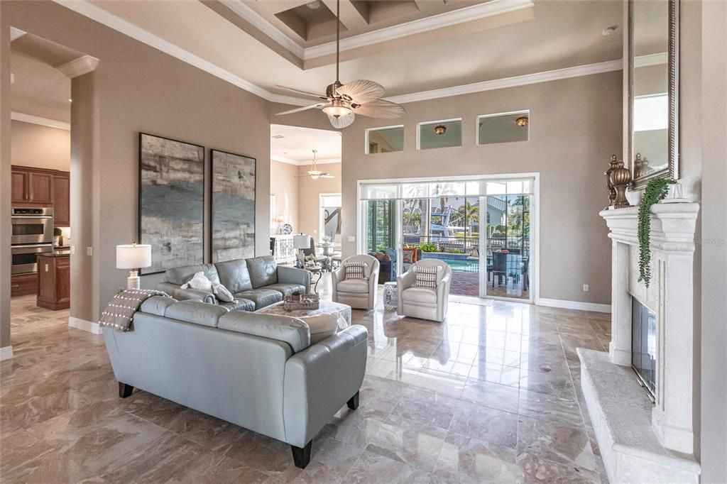 Exquisite living room is highlighted by 10' coffered ceilings, elegant columns, crown molding, and large windows with pool and canal views.