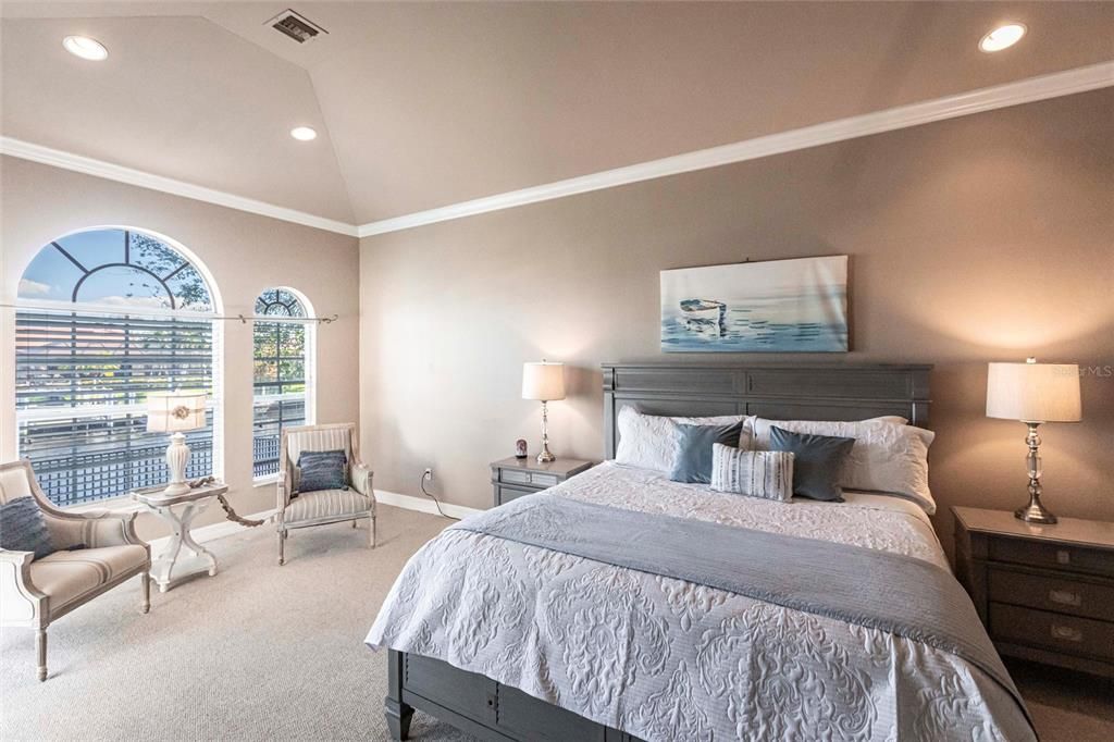 Primary suite retreat is a private sanctuary with lanai access, stunning canal views, arched windows, crown molding, and high ceilings.