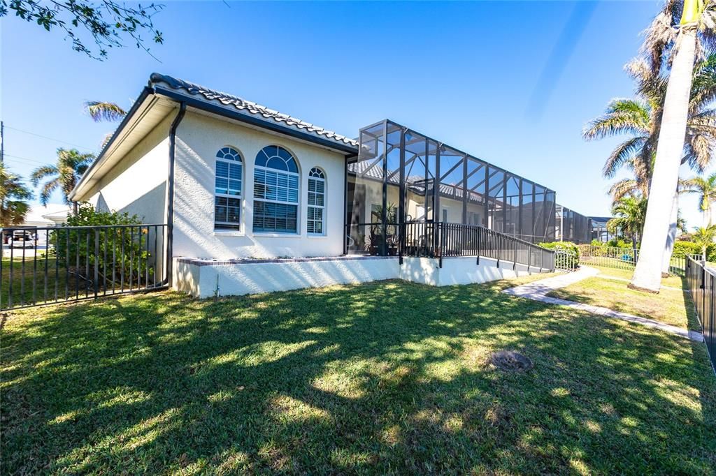 Rear exterior showcases grass lawn with convenienct sprinkler irrigation, and tall palms facing water frontage.