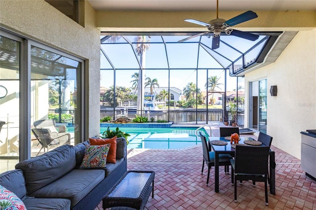 Step outside to your personal paradise. The expansive lanai features a brick-paver deck, a sparkling in-ground pool, and a summer kitchen complete with a JennAir grill, prep sink, and bar refrigerator—perfect for entertaining.