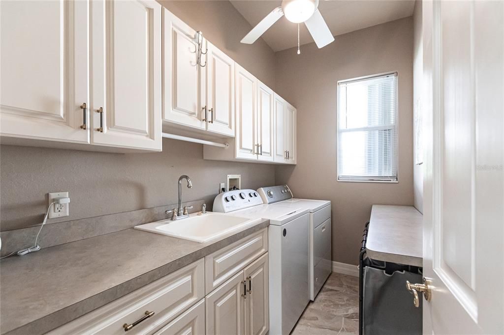 Laundry room featuring gas dryer, ceiling fan, and ample storage.