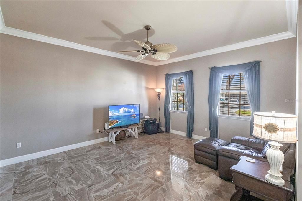 Front-facing office/den with French doors, ceiling fan, and multiple windows.