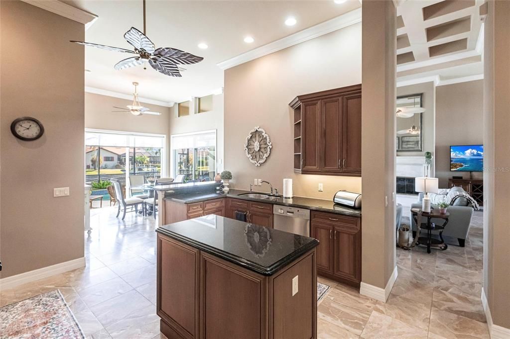 The gourmet kitchen is a chef’s dream, featuring granite countertops, custom wood cabinetry, a center island, breakfast bar, and premium stainless steel appliances, including a 6-burner gas range with hood and built-in double ovens.