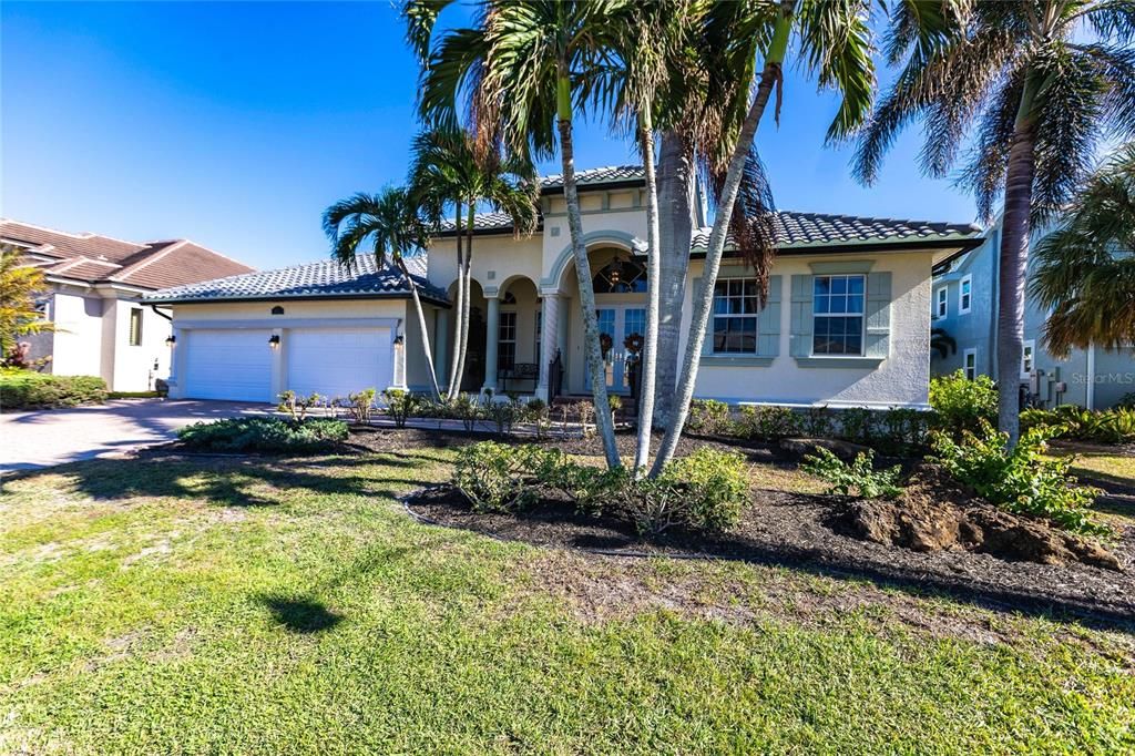 Front Exterior with large palms, grass lawn, and curated landscaping.